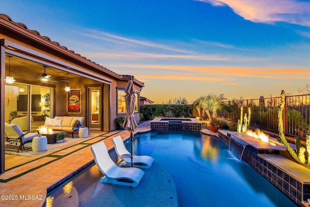 pool at dusk with an outdoor living space with a fire pit, a ceiling fan, a patio area, and a pool with connected hot tub