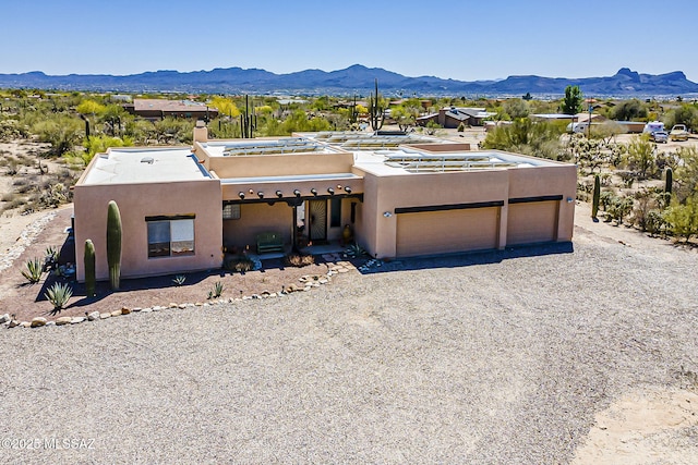 4247 W Flying Diamond Dr, Tucson, AZ 85742 - pueblo-style house featuring a mountain view, gravel driveway, an attached garage, and stucco siding