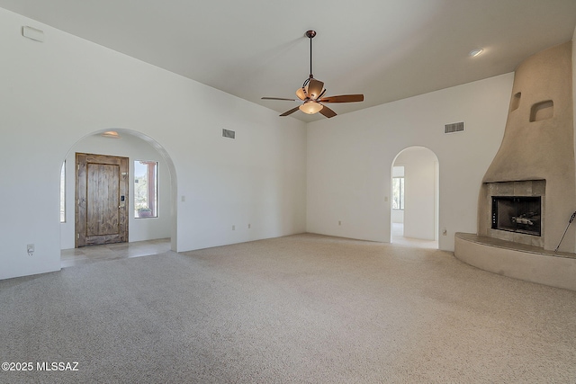 4247 W Flying Diamond Dr, Tucson, AZ 85742 - unfurnished living room featuring arched walkways, a large fireplace, ceiling fan, light carpet, and visible vents