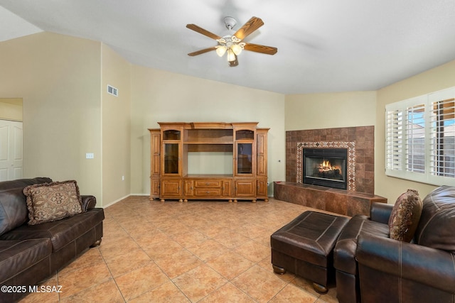 living room with a fireplace, light tile patterned floors, a ceiling fan, visible vents, and vaulted ceiling