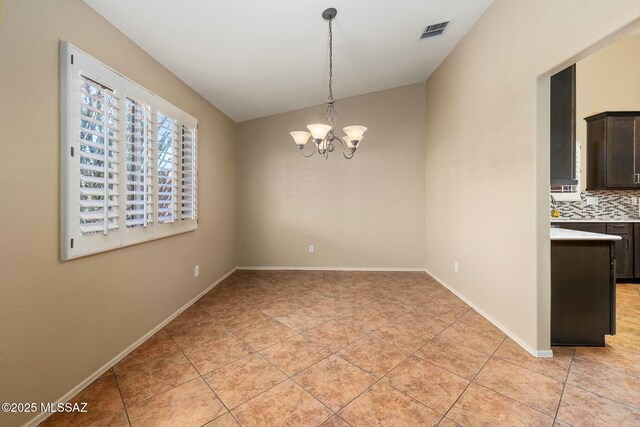 unfurnished dining area with light tile patterned floors, visible vents, baseboards, an inviting chandelier, and vaulted ceiling