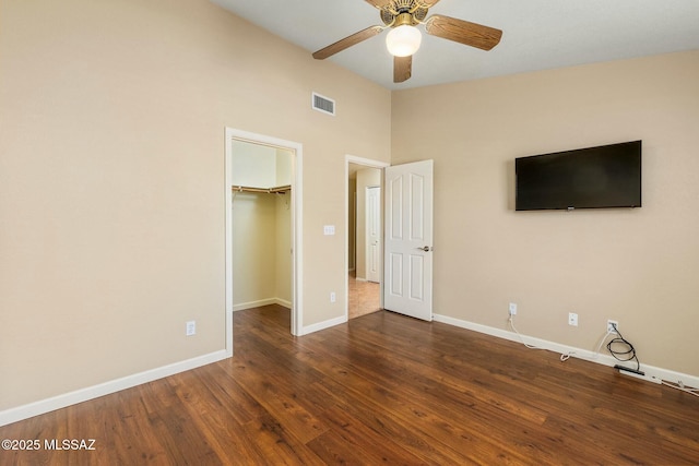 unfurnished bedroom featuring baseboards, visible vents, wood finished floors, and a spacious closet