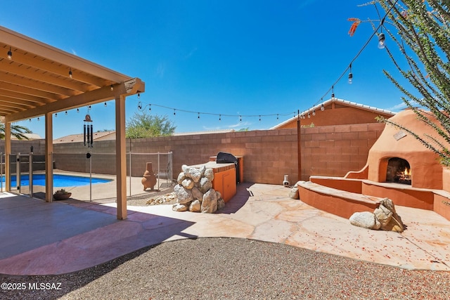 view of patio / terrace featuring a lit fireplace and a fenced backyard