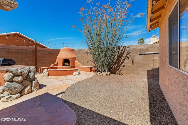 view of patio / terrace with a fenced backyard and a warm lit fireplace