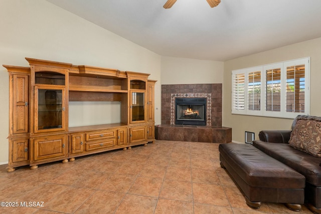 living room featuring a ceiling fan, light tile patterned flooring, a fireplace, and vaulted ceiling