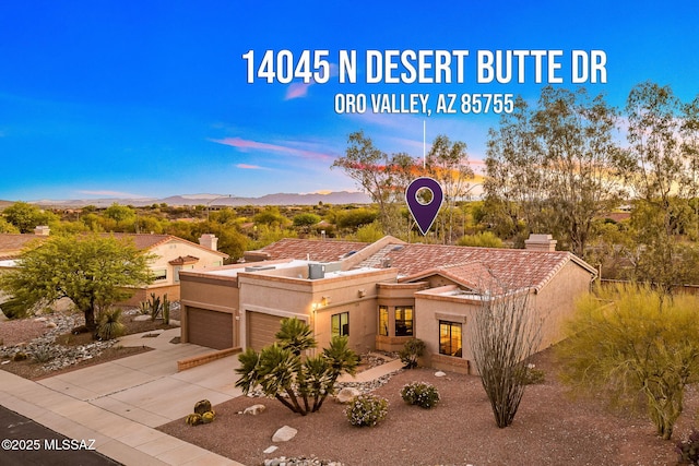 14045 N Desert Butte Dr, Oro Valley, AZ 85755 - exterior space with a chimney, a garage, a mountain view, concrete driveway, and stucco siding