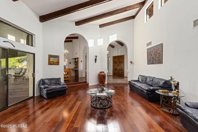 living area with hardwood / wood-style floors, arched walkways, visible vents, and a high ceiling
