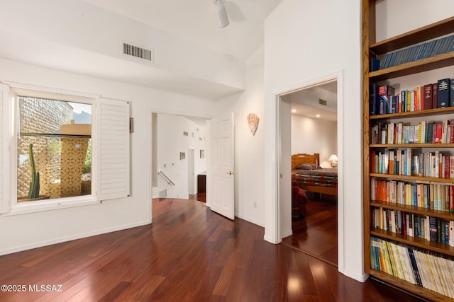 corridor with dark wood-style floors, baseboards, an upstairs landing, and visible vents