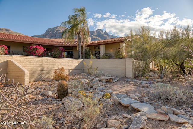 view of home's exterior featuring a tile roof, fence, and a mountain view