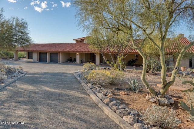 view of front facade featuring stucco siding, aphalt driveway, a tiled roof, and a garage