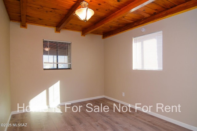 spare room featuring beamed ceiling, baseboards, wooden ceiling, and wood finished floors