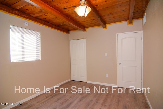 unfurnished bedroom with visible vents, baseboards, wooden ceiling, beamed ceiling, and wood finished floors