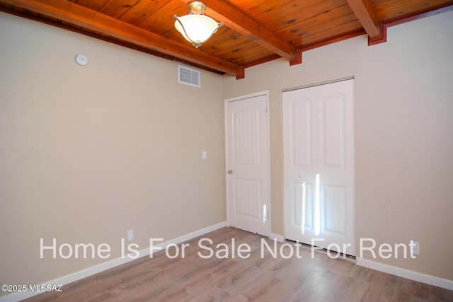 unfurnished bedroom with beamed ceiling, visible vents, wood ceiling, wood finished floors, and baseboards