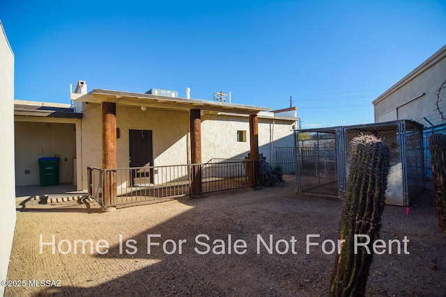 rear view of property with a patio area, stucco siding, fence, and a gate
