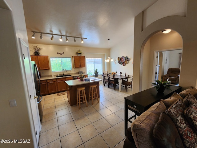 60464 E Blackcrest Loop, Tucson, AZ 85739 - kitchen with brown cabinetry, open floor plan, arched walkways, a sink, and light tile patterned floors
