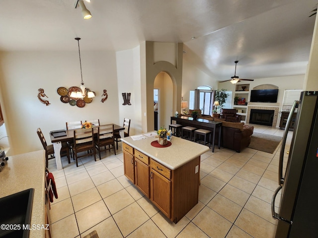 60464 E Blackcrest Loop, Tucson, AZ 85739 - kitchen featuring brown cabinets, light countertops, open floor plan, light tile patterned floors, and lofted ceiling