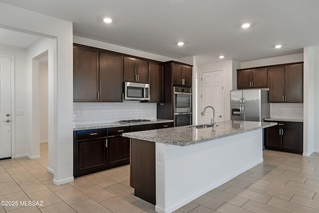 3352 W Shadow Park Way, Tucson, AZ 85742 - kitchen featuring a sink, stainless steel appliances, decorative backsplash, dark brown cabinetry, and light stone countertops