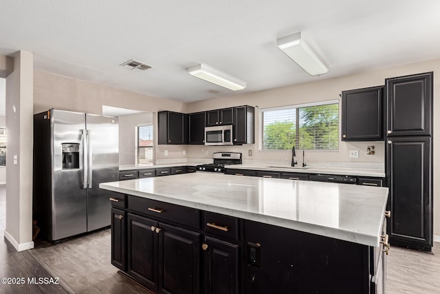 kitchen with a kitchen island, stainless steel appliances, visible vents, and dark cabinetry