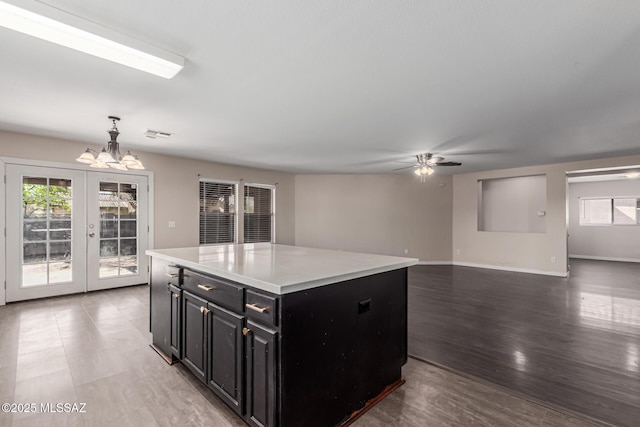 kitchen featuring dark cabinetry, light countertops, a wealth of natural light, and ceiling fan with notable chandelier