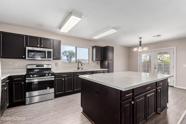 kitchen featuring dark cabinetry, light countertops, a sink, and appliances with stainless steel finishes