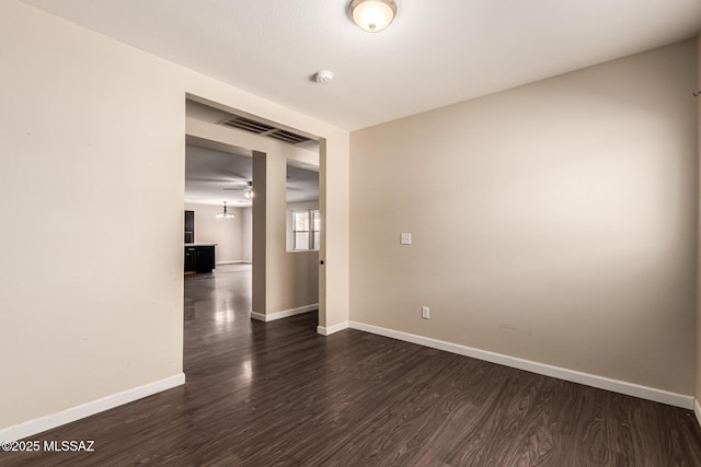 spare room with baseboards, visible vents, dark wood-style floors, and ceiling fan