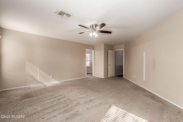 spare room with carpet floors, a ceiling fan, visible vents, and baseboards