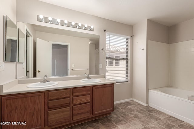full bath with baseboards, a sink, and double vanity