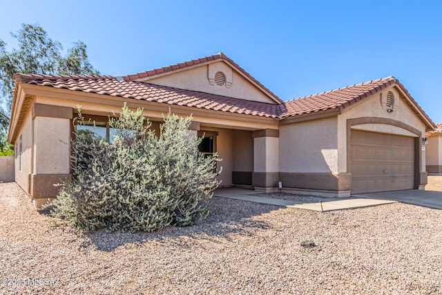 mediterranean / spanish-style house featuring stucco siding, a tile roof, concrete driveway, and a garage