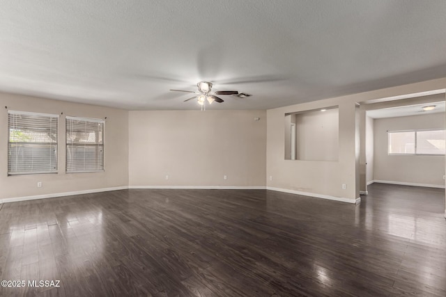 unfurnished room with a textured ceiling, ceiling fan, baseboards, dark wood-style flooring, and visible vents