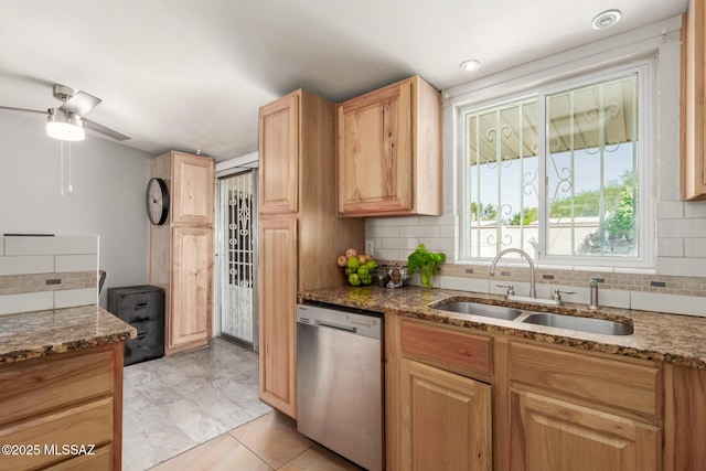 kitchen featuring stainless steel dishwasher, light brown cabinetry, a sink, tasteful backsplash, and stone countertops