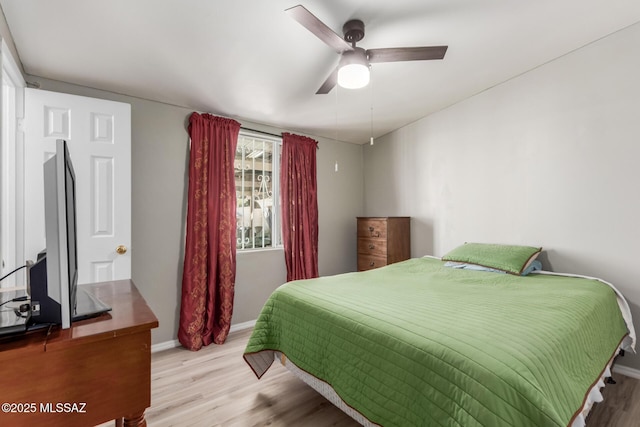 bedroom featuring ceiling fan, baseboards, and wood finished floors