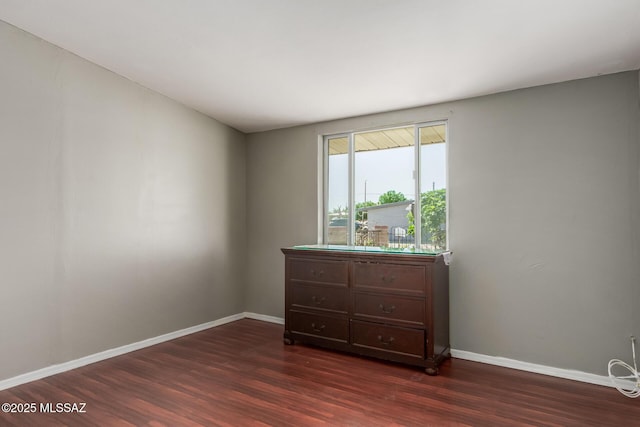 bedroom featuring baseboards and dark wood-style flooring