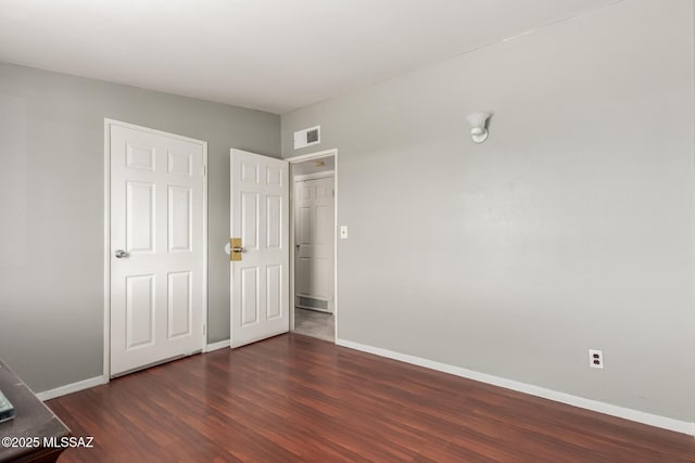 unfurnished bedroom featuring baseboards, visible vents, and dark wood-type flooring