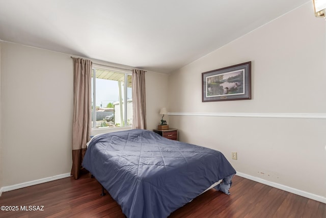 bedroom with baseboards, vaulted ceiling, and wood finished floors