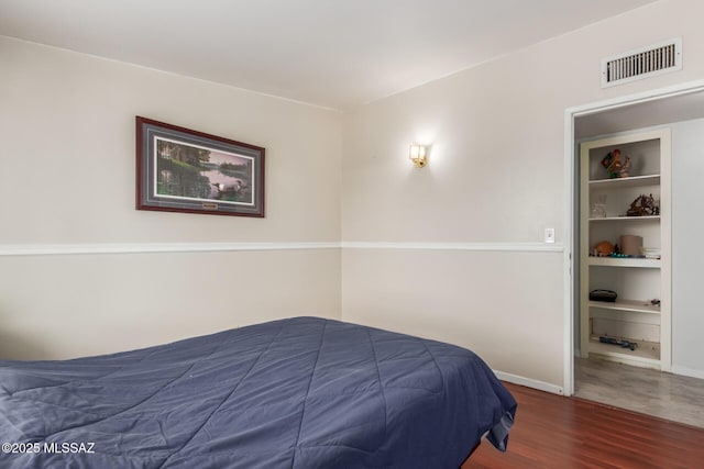 bedroom with wood finished floors, visible vents, and baseboards
