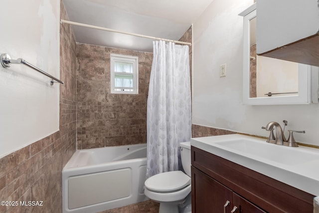 bathroom with a wainscoted wall, shower / bath combination with curtain, toilet, vanity, and tile walls