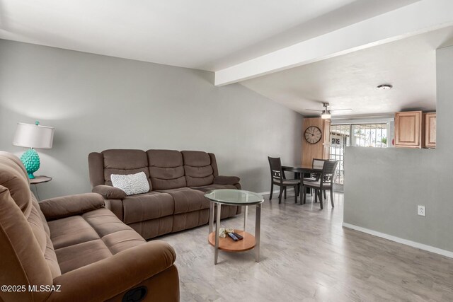 living room with light wood-type flooring, ceiling fan, baseboards, and beamed ceiling