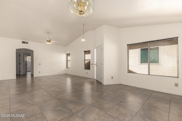 spare room with arched walkways, a healthy amount of sunlight, vaulted ceiling, and visible vents