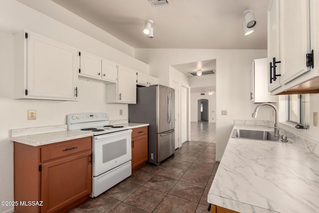 kitchen featuring a sink, vaulted ceiling, freestanding refrigerator, light countertops, and white range with electric stovetop