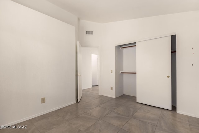 unfurnished bedroom featuring baseboards, visible vents, tile patterned flooring, and a closet