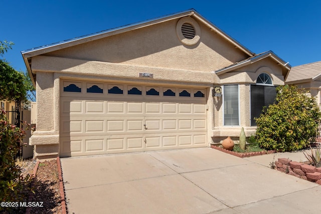 view of front of house with stucco siding, an attached garage, and concrete driveway