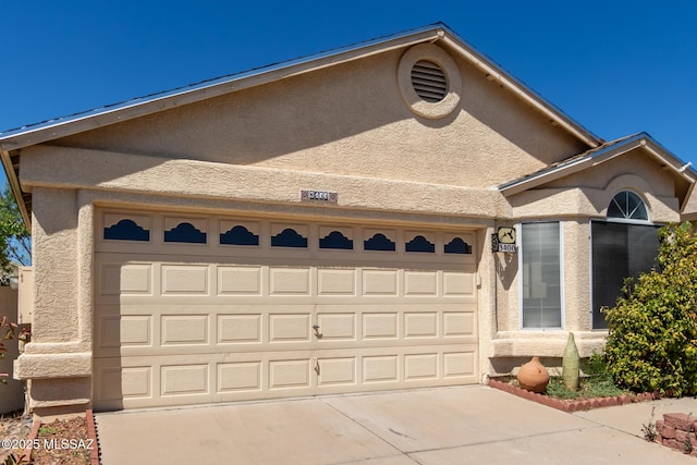 ranch-style home featuring an attached garage, driveway, and stucco siding