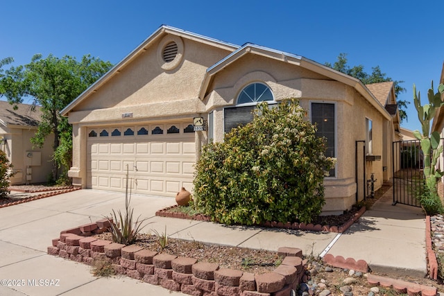ranch-style home with concrete driveway, an attached garage, a gate, and stucco siding