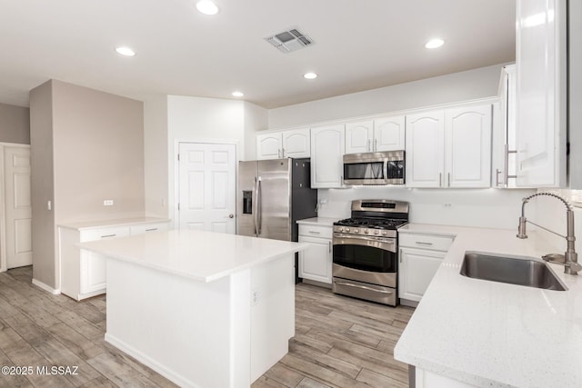 kitchen featuring light wood-style floors, appliances with stainless steel finishes, white cabinetry, and a sink