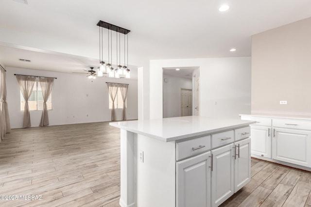 kitchen featuring open floor plan, light wood-style floors, ceiling fan, light countertops, and white cabinets