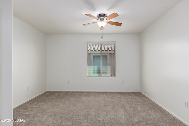 carpeted spare room with a ceiling fan and baseboards