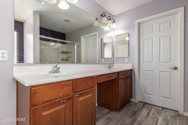 full bathroom with a shower stall, double vanity, visible vents, wood finished floors, and a sink