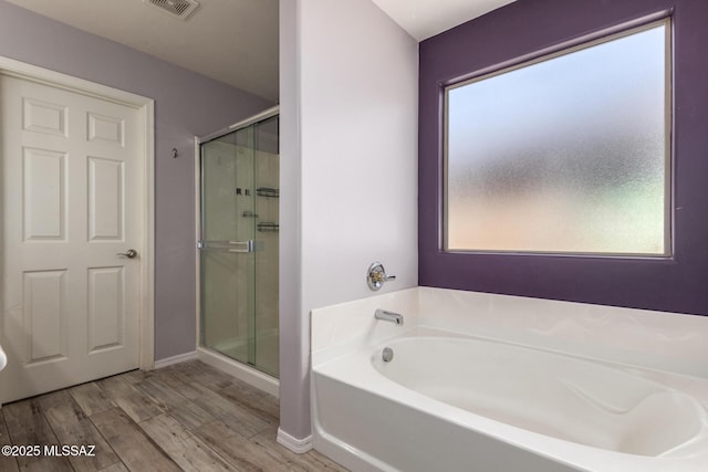 full bath featuring a stall shower, visible vents, baseboards, wood finished floors, and a garden tub