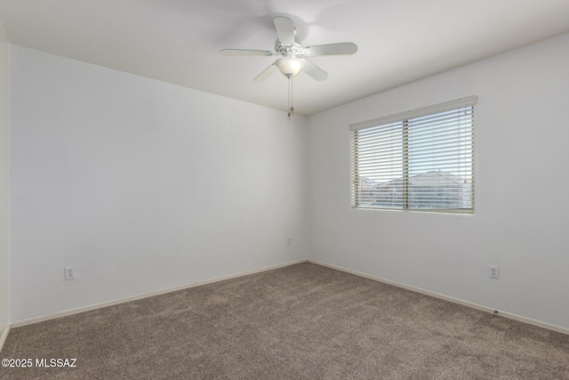 carpeted spare room featuring a ceiling fan and baseboards