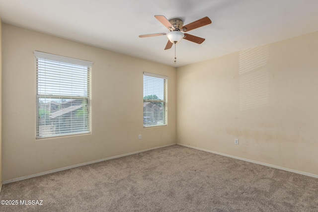 carpeted empty room with a ceiling fan and baseboards